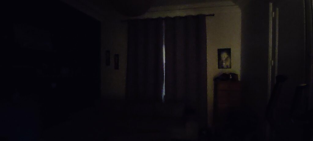 Le salon dans la pénombre à 8h du matin, rideaux fermés, un filet de lumière entre les deux pans